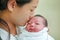 Closeup mother kissing infant baby in her arms in hospital after delivery room