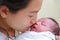 Closeup mother kissing infant baby in her arms in hospital after delivery room