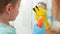 Closeup of mother and little son cleaning and washing mirror in bathroom with sponges and chemical detergent