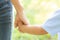 Closeup mother or parent and son holding hand with love together in summer outside in the park