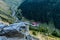 Closeup of a mountain rock with mountain chalet and big forest at the bottom of the mountain and cars passing on a curvy mountain