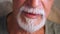Closeup of the mouth of a man with a white beard speaking