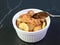 Closeup Mouthwatering Banana Walnut Bread Pudding in a Ceramic Bowl Isolated on Black Table