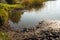 Closeup of the muddy shore of a Dutch lake in low early morning