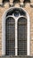 Closeup of a mullioned window in white stone on brick wall. Window with railing