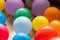 A closeup of multiple vibrant balloons lying on a living room floor indoor of a house. The fun decorations are ready for a home