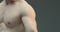 Closeup muscular male with naked torso showing biceps and triceps muscles on gray studio background. Shirtless athlete