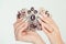 Closeup nail polished pastel multicolored long nails coral pink white with crystals hand holding black dark diamond crown broach