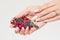 Closeup nail polished pastel multicolored long nails coral pink, white with crystals, hand holding perfume magenta blue green