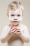 Closeup Natural Portrait of One Little Smiling Child With Food in Hands While Greedily Eating Red Apple Posing Against Beige