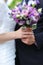 Closeup nice vioelt bouquet of flowers in fiancee and groom hands.
