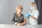 Closeup nurse doing vaccine injection to senior woman.