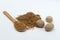 Closeup of nutmeg powder, wooden spoon and whole nutmegs on the white background