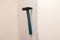 Closeup of old black iron hammer with shabby blue wooden handle stuck into a white wall. Ð¡oncept of repair, reconstruction,