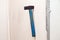 Closeup of old black iron hammer with shabby blue wooden handle stuck into a white wall. Ð¡oncept of repair, reconstruction,