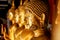 Closeup old and golden face of golden Buddha statue on blurred golden Buddha statue stand strong line background