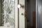 Closeup of old home white wooden door with stained glass, metal lattice. Open vintage entrance doorway, round handle, broken lock
