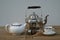 Closeup of an old water kettle with teapot, teacup, tea infuser and candy