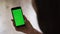 Closeup of old woman hand holding a mobile phone with a vertical green screen spbi. Chroma key