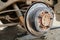 Closeup old, worn out and rusty car brake system. Rear disc brake of a car with a removed wheel. Shallow focus.