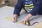 Closeup of an older woman in a furniture factory who is measuring and marking a grey material for the sofa with a chock