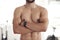 Closeup of one fit topless mixed race man with big strong muscles from regular exercise standing with arms crossed in a