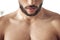 Closeup of one fit topless mixed race man with strong defined pectoral muscles from regular exercise in a gym