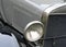 Closeup of a one of the headlamps of an antique car