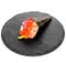 Closeup of one piece of sushi on a black round board isolated on white