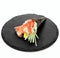 Closeup of one piece of sushi on a black round board isolated on white