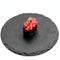 Closeup of one piece of sushi on a black round board isolated on white