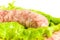 Closeup of one Uncooked Sausage on salad leaf