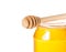 Closeup of opened honey jar on white background with wooden honey dipper