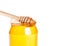 Closeup of opened honey jar on white background with wooden honey dipper inside
