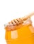 Closeup of opened honey jar on white background with wooden honey dipper inside