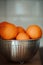 Closeup oranges in a metal bowl, isolated background