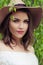 Closeup outdoors portrait of young woman face. Pretty girl in hat