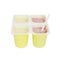 Closeup of a pack of four yogurts in yellow plastic cups with a plastic spoon on a white background