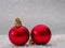 Closeup of a pair of vibrant red Christmas ornaments set on a snowy surface with blurred background