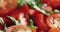 Closeup pan of cherry tomatoes with arugula salad in white bowl