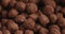 Closeup pan of chocolate cereal balls in white bowl for breakfast on wooden table