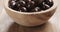 Closeup pan of chocolate covered almonds in wood bowl on table