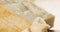 Closeup pan of hard parmesan cheese cubes on olive cutting board