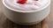 Closeup pan of organic strawberry yogurt on wooden table