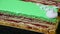 Closeup panorama at green glazed layered cake portions served on black tray