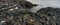 Closeup panorama shot of rocky basalt volcanic textured columns in Kalfshamarsvik in Iceland during rainy weather.