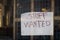 Closeup of a paper with "Staff Wanted" writing duck taped on glass door