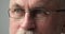 Closeup part of face older man in glasses looks aside
