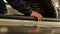 Closeup of a passenger hand lifting on escalator handrail. Female hand on black rubber handrail of an escalator moving up