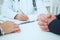 Closeup of patients hands and doctor taking notes.